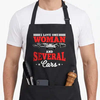 Several auto mechanic apron - Red and white text I Love One Woman And Several Cars above five black and white classic — shown on a black cotton canvas apron against a white background