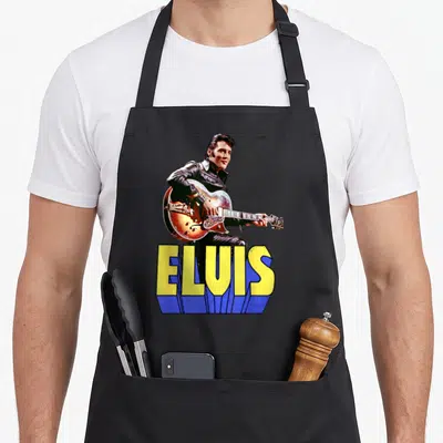 Elvis screenwriting apron - Photo of Elvis Presley with guitar above yellow text ELUIS with blue shadow — shown on a black cotton canvas apron against a white background