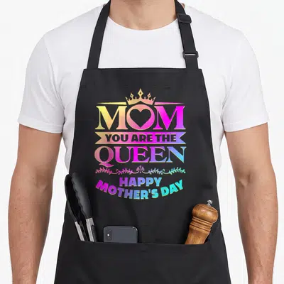 Queen mother's day aprons - Stacked text MOM YOU ARE THE QUEEN HAPPY MOTHER'S DAY with crown heart and floral scroll — shown on a black cotton canvas apron against a white background