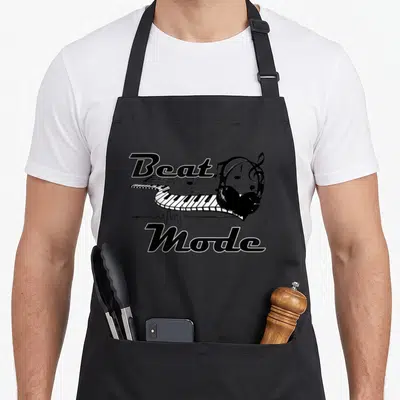 Beat producer lover apron - Black and white curved keyboard with headphones and Beat Mode text — shown on a black cotton canvas apron against a white background