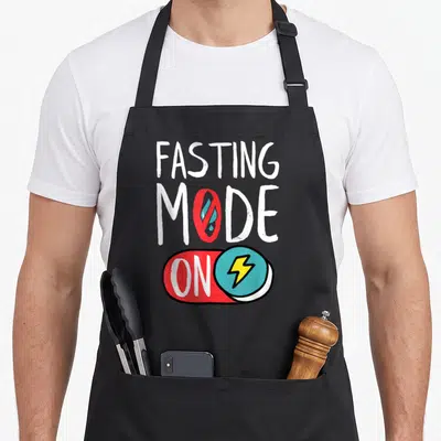 Autophagy intermittent fasting apron - Fasting Mode On toggle switch with lightning bolt and prohibition sign — shown on a black cotton canvas apron against a white background