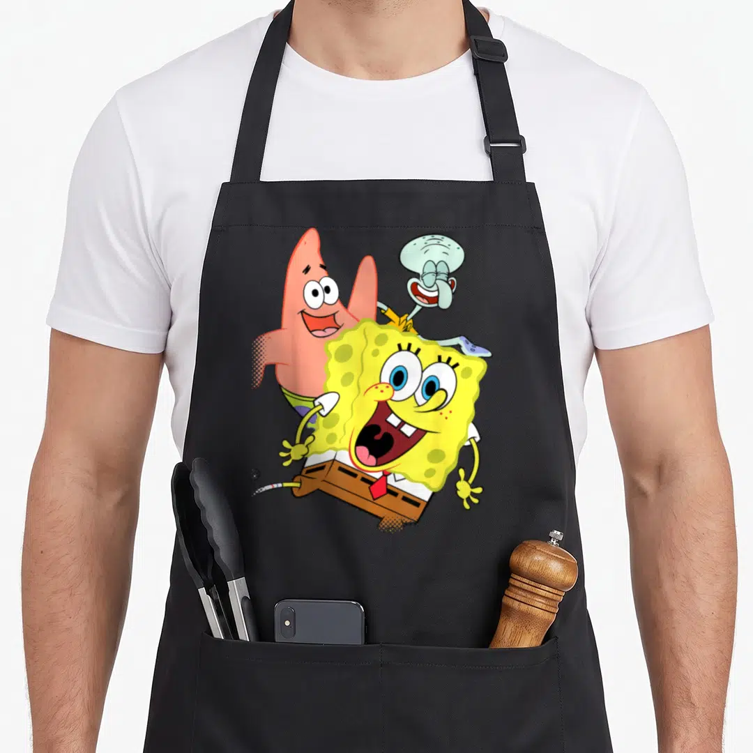 Squidward patricks apron - SpongeBob, Patrick starfish and Squidward in yellow pink blue cartoon pose — shown on a black cotton canvas apron against a white background