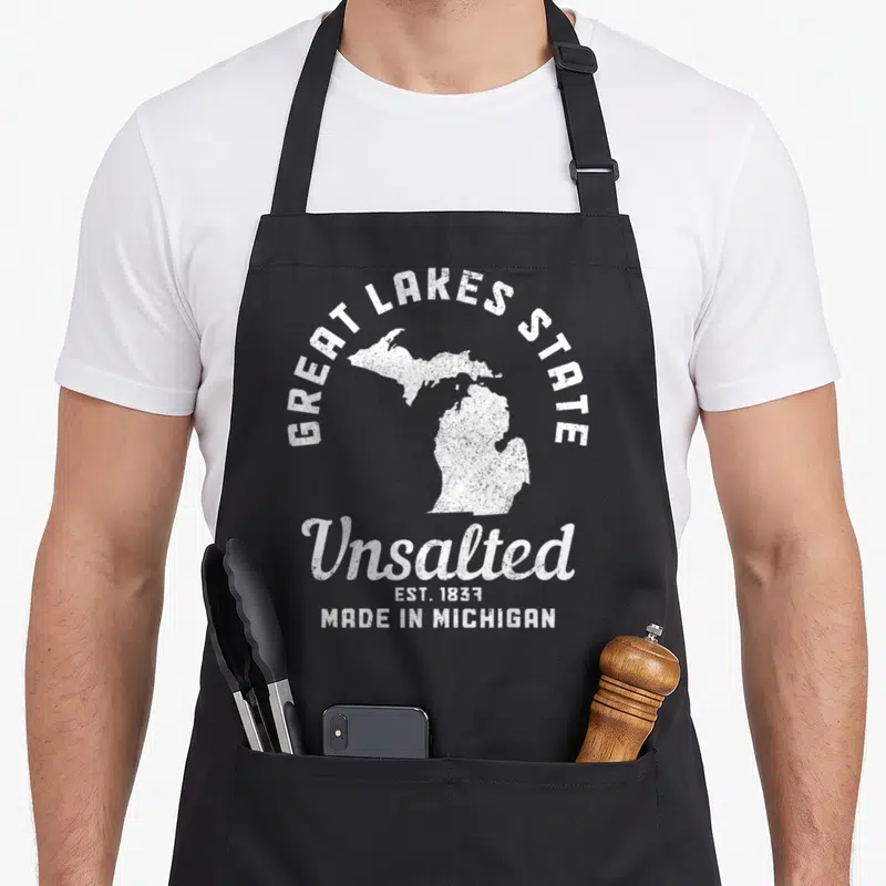 Michigan lake pride apron - White distressed Michigan map with Great Lakes State and Unsalted text — shown on a black cotton canvas apron against a white background