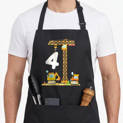 Digger vehicle apron - Cartoon crane lifting white number 4 above excavator and bulldozer on dirt — shown on a black cotton canvas apron against a white background