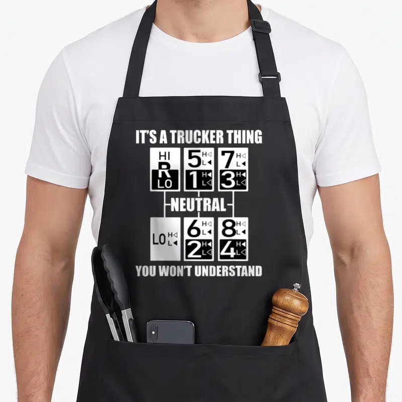 Gear semi truck apron - Black and white gear shift diagram with text IT'S A TRUCKER THING and numbers 1 through 8 — shown on a black cotton canvas apron against a white background