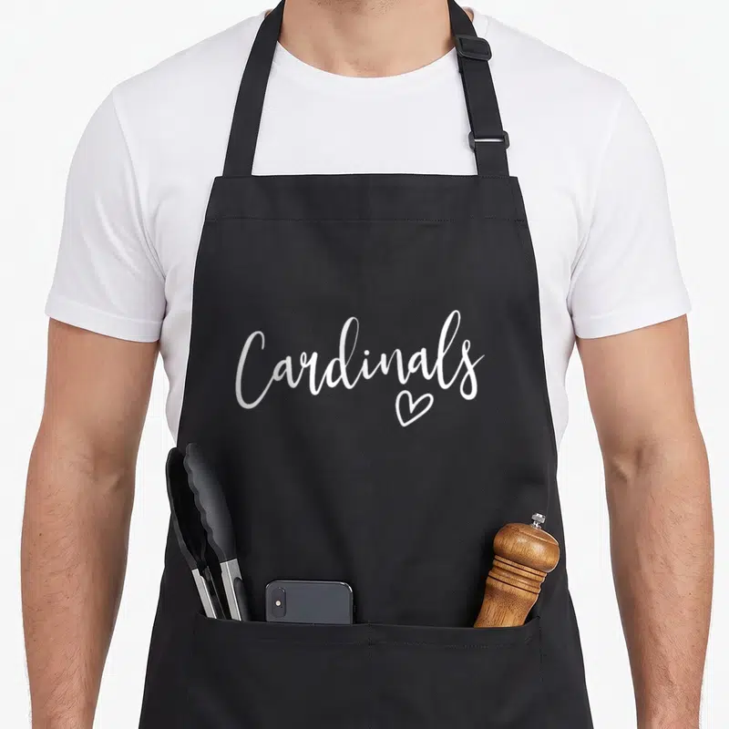 Cardinal sports team aprons - White script text reading Cardinals with a heart outline below the letters — shown on a black cotton canvas apron against a white background