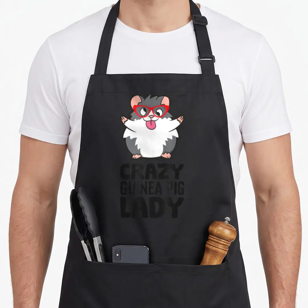 Cool guinea pet apron - Cartoon guinea pig with red glasses above stacked text CRAZY GUINEA PIG LADY — shown on a black cotton canvas apron against a white background