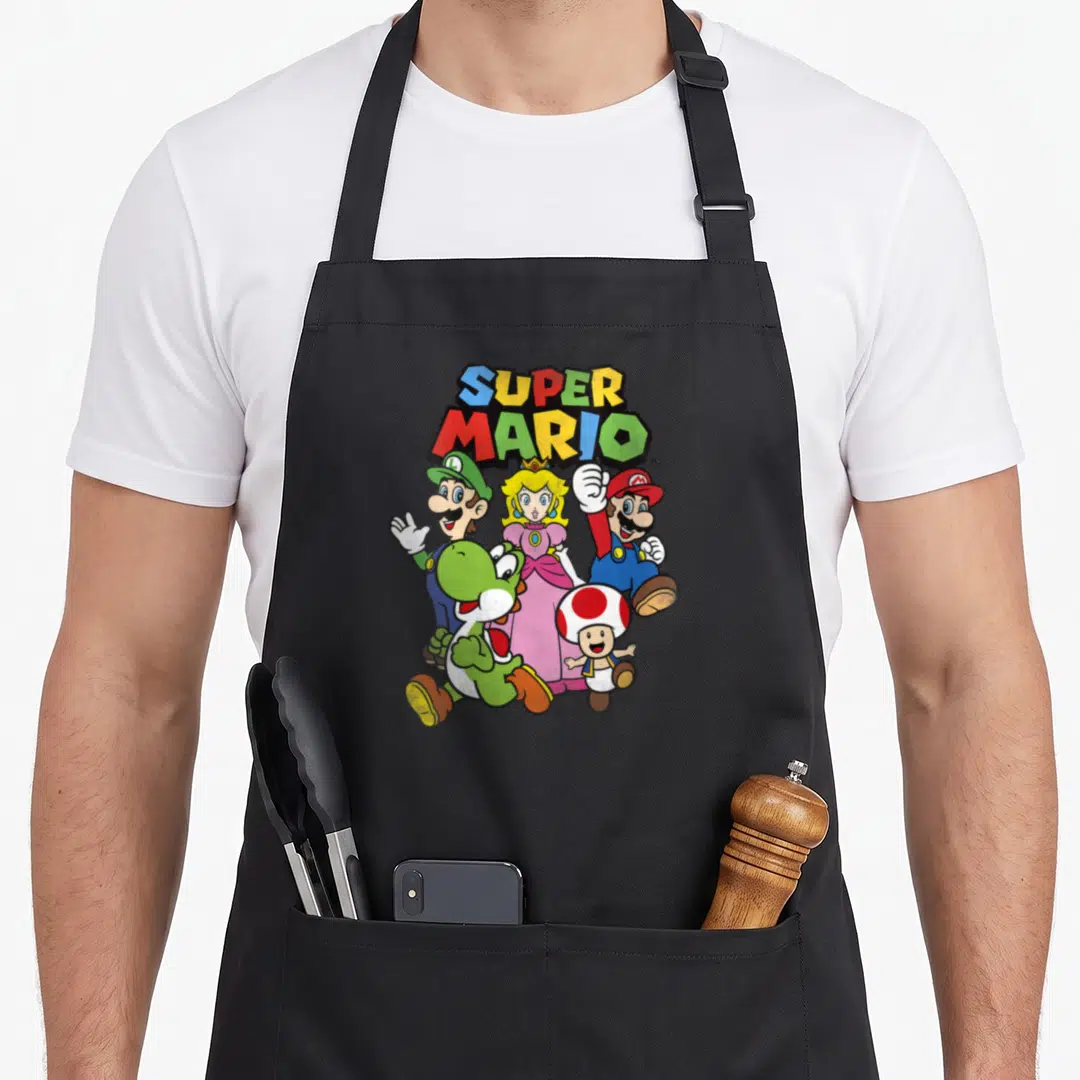 Funny heroe apron - SUPER MARIO text above five cartoon characters in red blue yellow green and pink — shown on a black cotton canvas apron against a white background