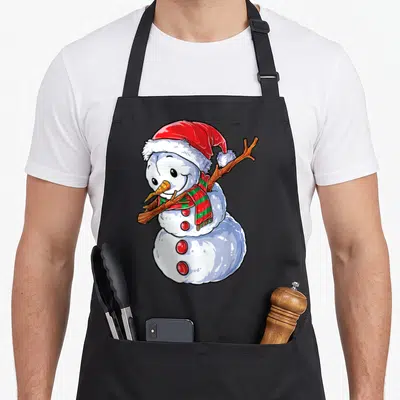 Dabbing snowman apron - Cartoon snowman in red hat and striped scarf holding a stick arm in a pose — shown on a black cotton canvas apron against a white background