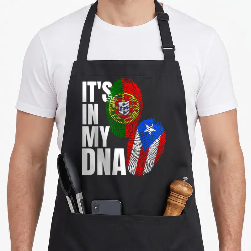 Mix portuguese apron - Stacked text IT'S IN MY DNA beside fingerprint shaped Portuguese and Puerto Rican flags — shown on a black cotton canvas apron against a white background