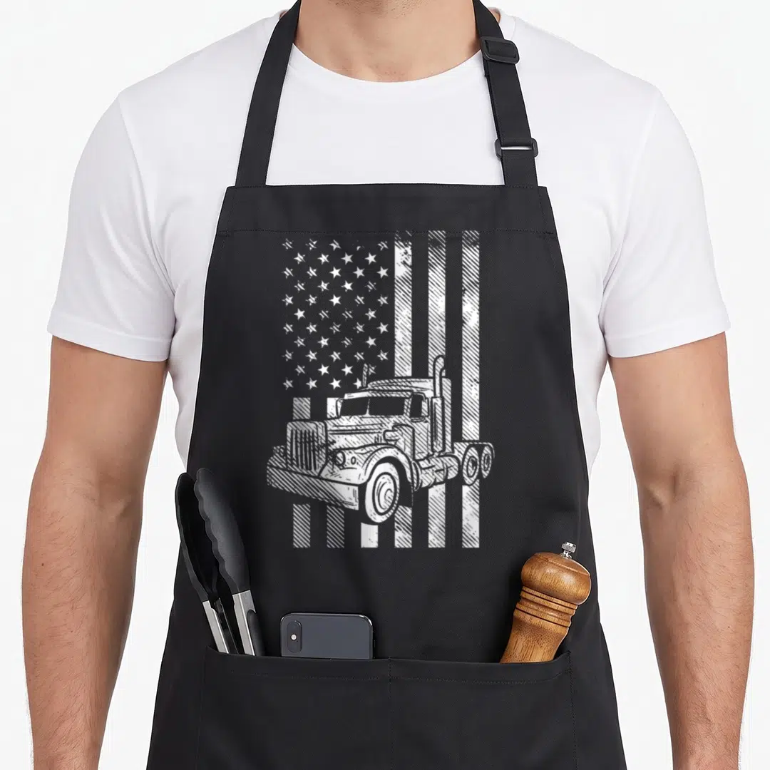 Trucking american flag apron - White line art of a semi-truck positioned in front of a distressed American flag pattern — shown on a black cotton canvas apron against a white background