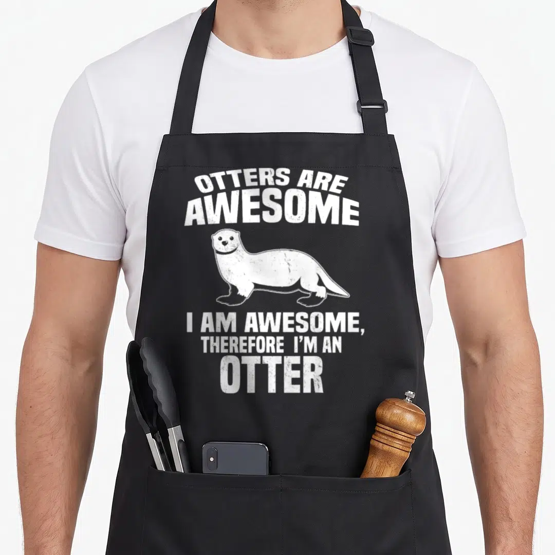 Otter distressed apron - White cartoon otter centered between arched and straight distressed text blocks — shown on a black cotton canvas apron against a white background