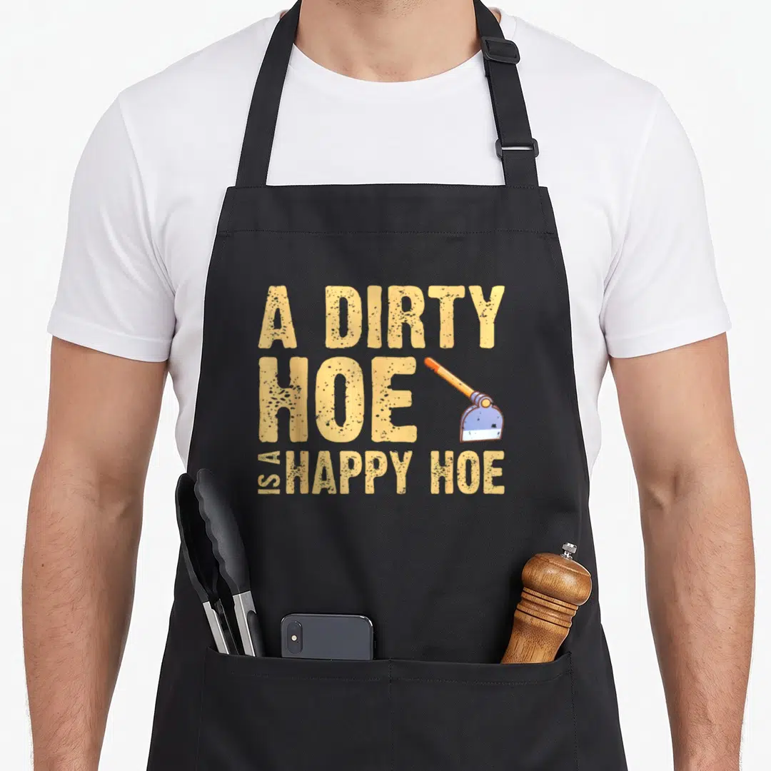 Dirty gardener apron - Distressed text A DIRTY HOE IS A HAPPY HOE with an orange handle blue blade hoe graphic — shown on a black cotton canvas apron against a white background