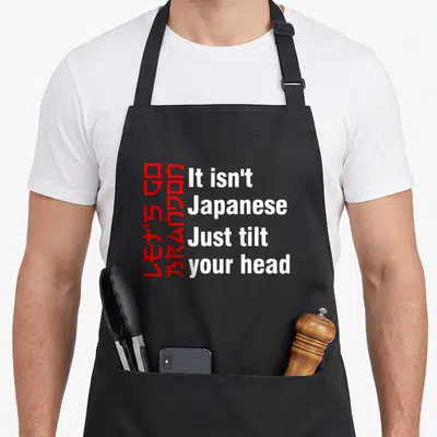 Brandon tilt apron - Red rotated text and white horizontal words forming a visual pun on a grey background — shown on a black cotton canvas apron against a white background