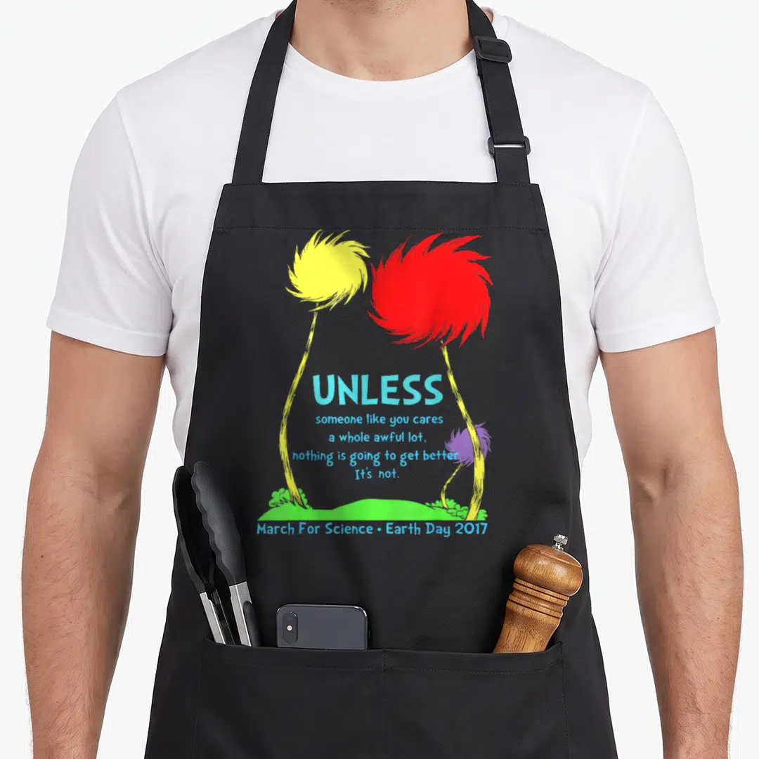March science apron - Yellow and red truffula trees framing blue text about caring for the environment — shown on a black cotton canvas apron against a white background
