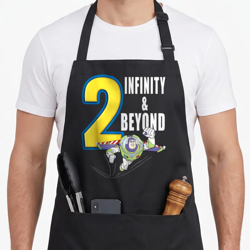 Fly dog breed aprons - Yellow number 2 and Buzz Lightyear flying next to Infinity Beyond text — shown on a black cotton canvas apron against a white background