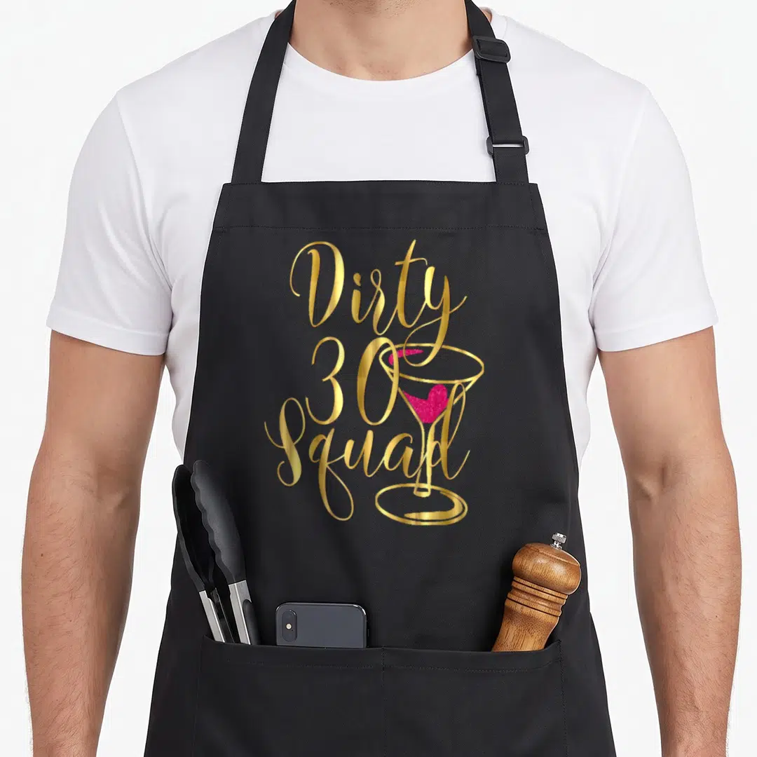 Bestie funny dirty aprons - Gold Dirty 30 Squad text with pink cocktail glass graphic — shown on a black cotton canvas apron against a white background