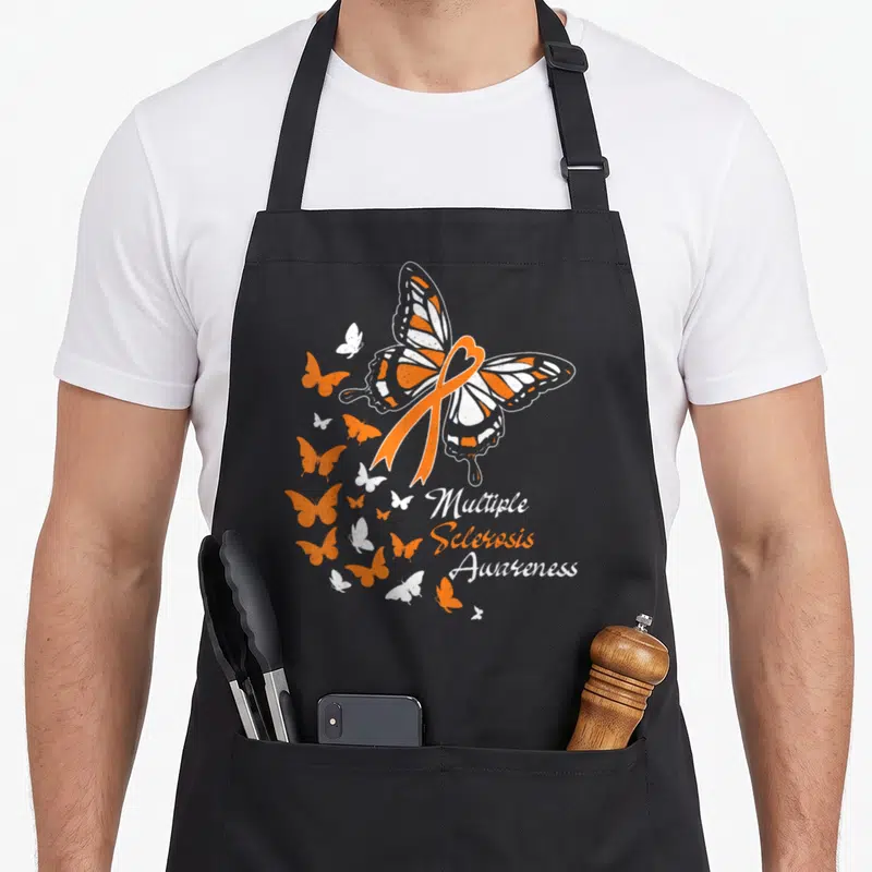 Multiple butterfly apron - Orange ribbon heart over butterfly with scattered wings and stacked awareness text — shown on a black cotton canvas apron against a white background