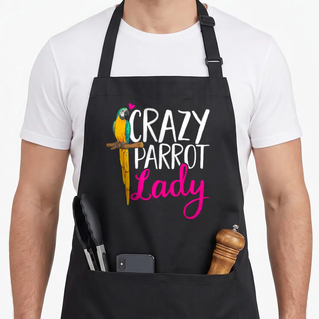 Macaw crazy parrot lady apron - Cartoon blue and yellow parrot on branch next to white and pink text reading Crazy — shown on a black cotton canvas apron against a white background