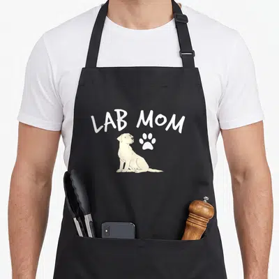 Puppy labrador apron - LAB MOM text above cream sitting dog and white paw print — shown on a black cotton canvas apron against a white background