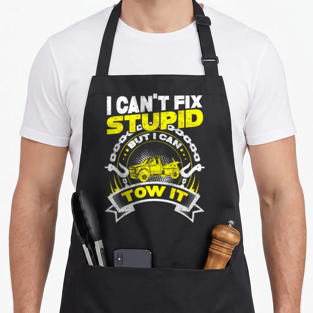 Tow truck apron - Yellow tow truck graphic with chain hooks and sarcastic text in distressed font — shown on a black cotton canvas apron against a white background