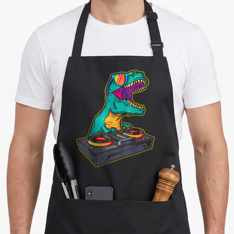 Floppy t-rex apron - Teal cartoon T-Rex with blue sunglasses behind a black DJ controller with two turntables — shown on a black cotton canvas apron against a white background
