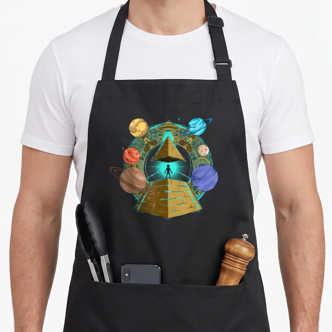 Pyramid science apron - Gold pyramid with black alien silhouette, hovering UFO, and surrounding planets inside a carved — shown on a black cotton canvas apron against a white background