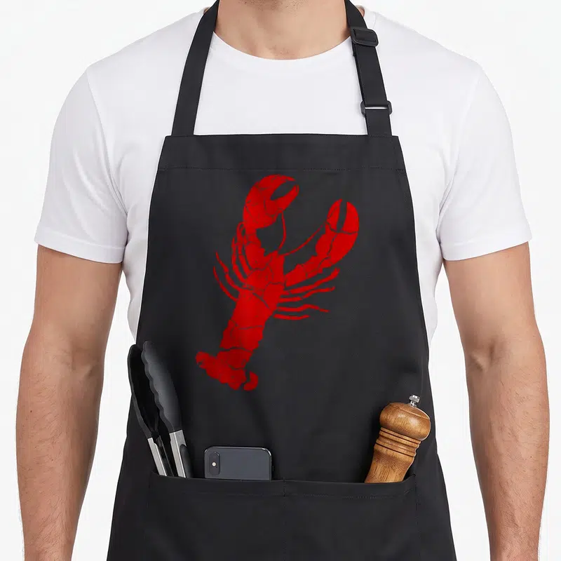 Vintage lobster apron - Red distressed lobster illustration with cracked texture on plain background — shown on a black cotton canvas apron against a white background