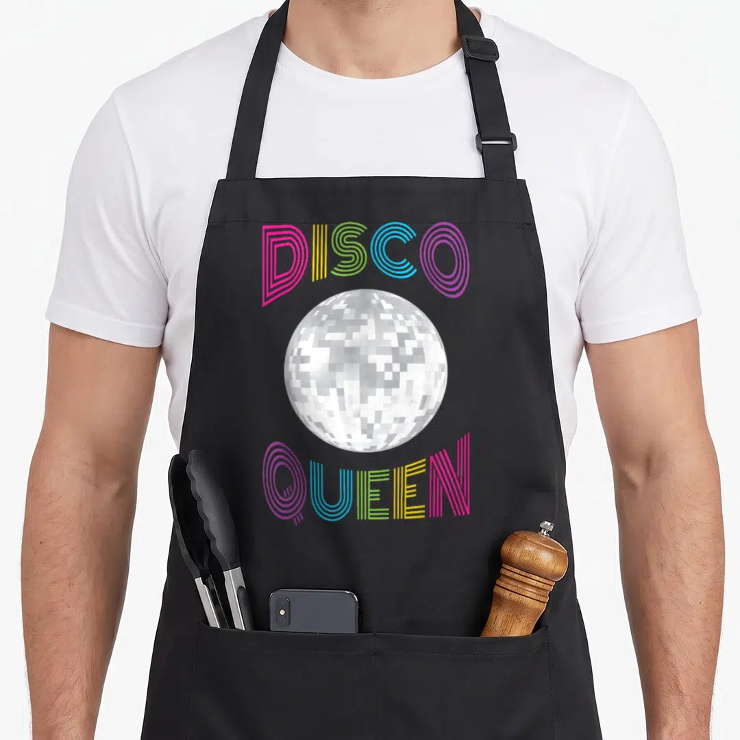 Queen seventy 70s apron - Silver disco ball surrounded by arched multi-colored lines spelling DISCO QUEEN — shown on a black cotton canvas apron against a white background