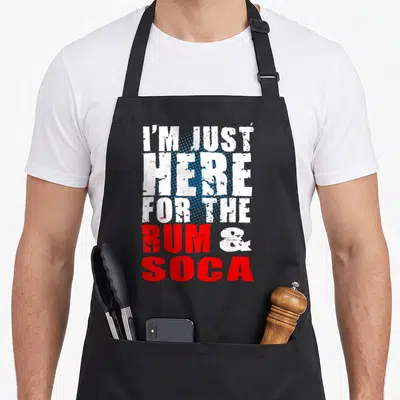 Rum carnival apron - Stacked distressed text I'M JUST HERE FOR THE RUM & SOCA with blue halftone dots — shown on a black cotton canvas apron against a white background