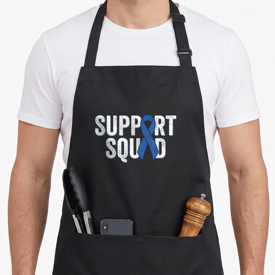 Colon ribbon apron - SUPPORT SQUAD text with vertical blue ribbon overlapping letters in distressed white font — shown on a black cotton canvas apron against a white background