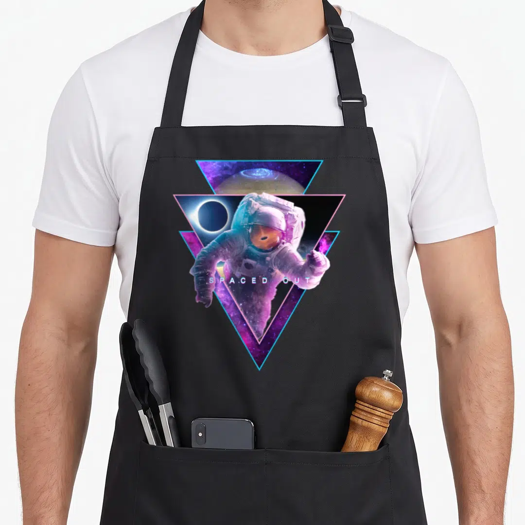 Astronaut cosmonaut apron - Astronaut in purple and blue triangles with black hole reflection and text spaced out — shown on a black cotton canvas apron against a white background