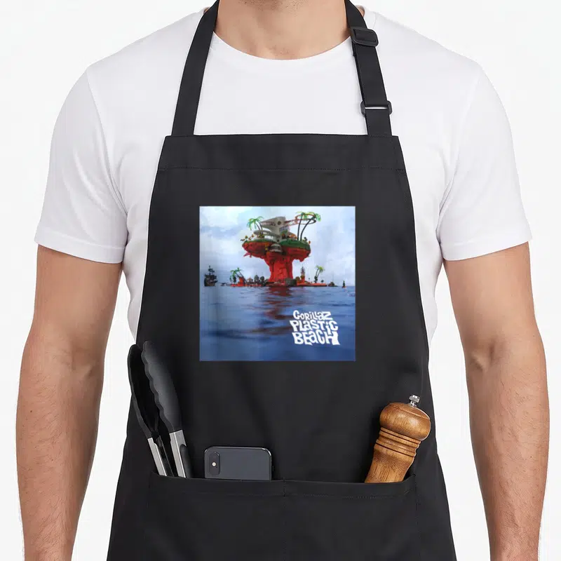Gorillaz gorilla mom apron - Surreal red island with house and white text on blue water — shown on a black cotton canvas apron against a white background