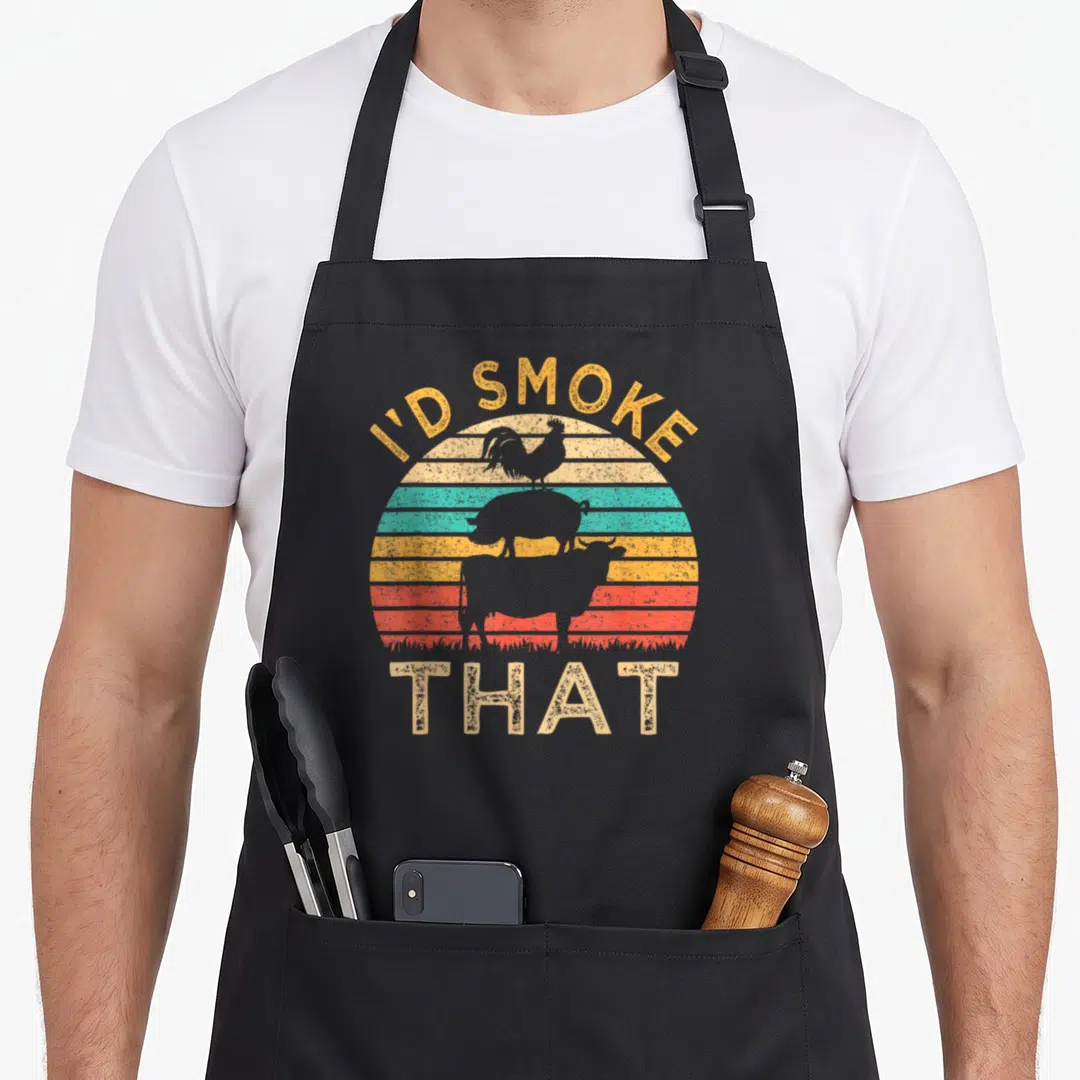 Funny barbeque i'd smoke that apron - Retro sunset with stacked rooster pig cow silhouettes and text I'D SMOKE THAT — shown on a black cotton canvas apron against a white background