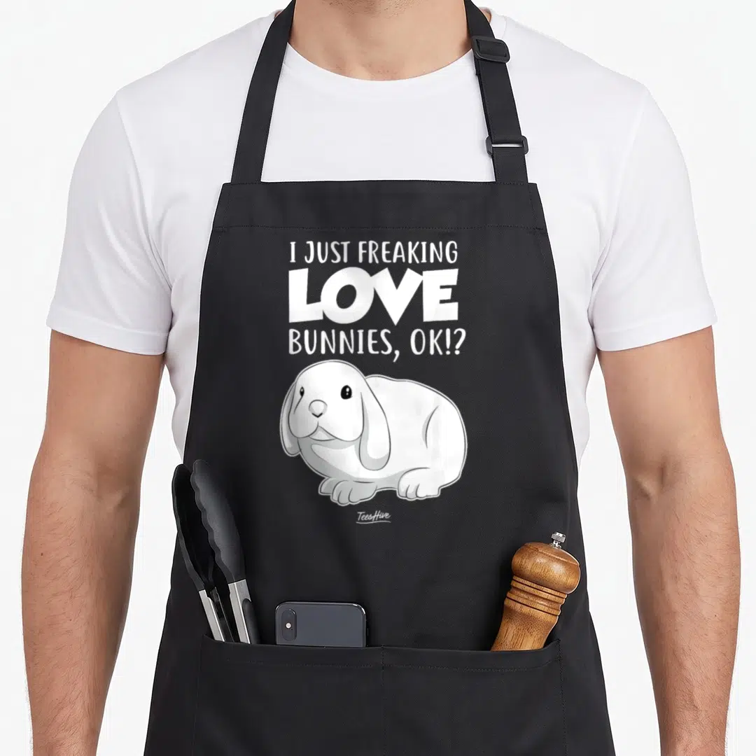 Freaking bunny apron - White text reading I Just Freaking Love Bunnies OK above a cartoon rabbit illustration — shown on a black cotton canvas apron against a white background