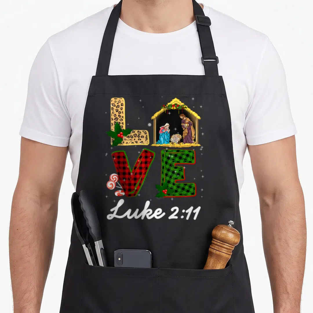 Leopard christmas plaid apron - LOVE letters with nativity scene as O and Luke 2:11 text below — shown on a black cotton canvas apron against a white background