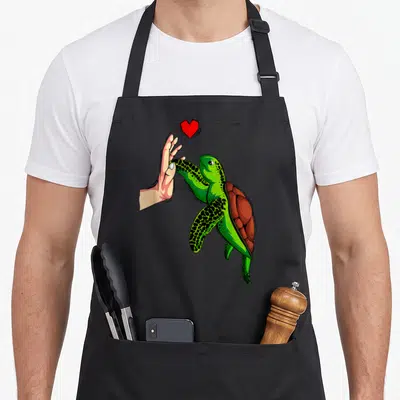 Retro turtle lover apron - Cartoon sea turtle and hand high-fiving with a red heart floating above in green and brown — shown on a black cotton canvas apron against a white background