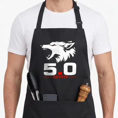 Coyote animal apron - White coyote head above 5.0 text flanked by red lines — shown on a black cotton canvas apron against a white background