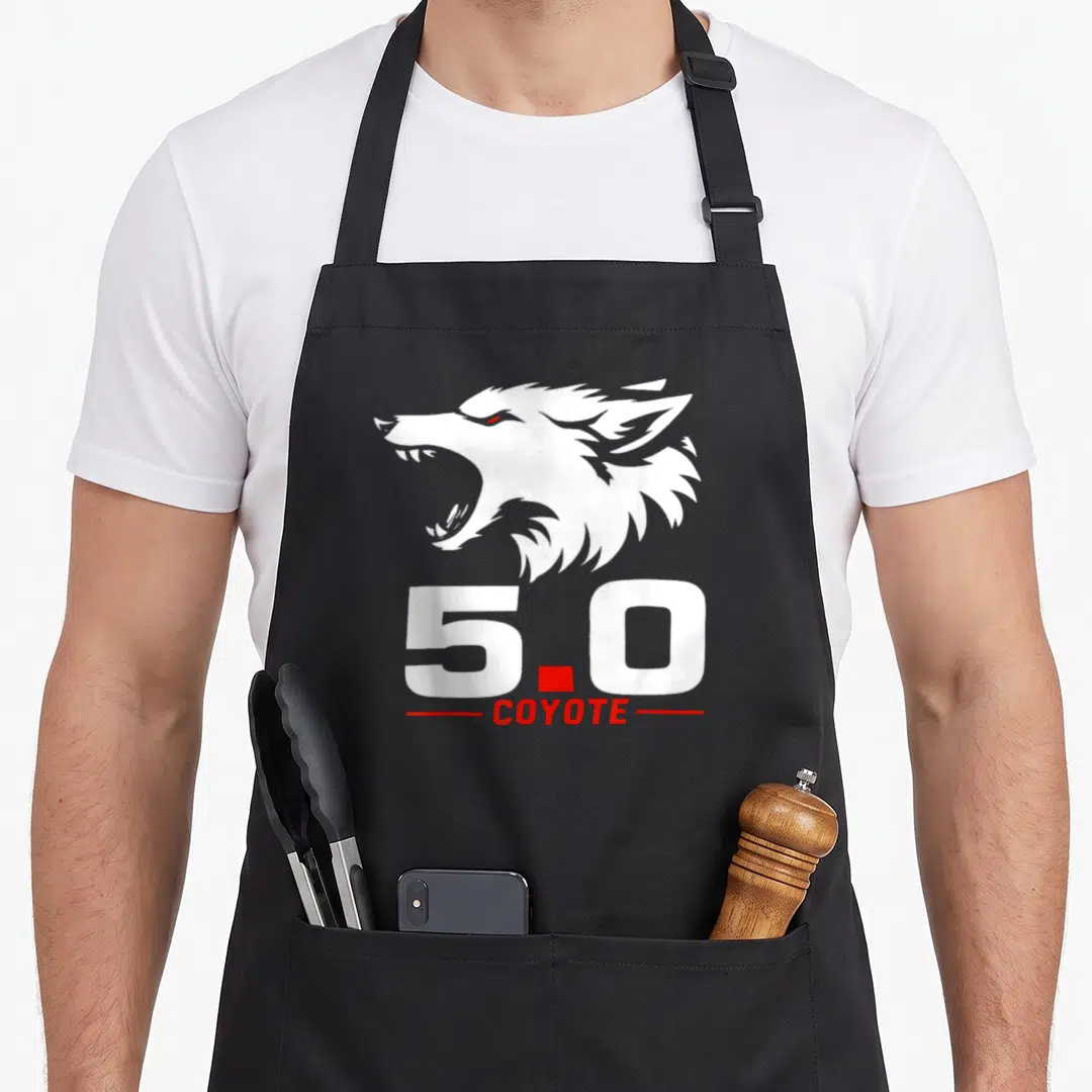 Coyote animal apron - White coyote head above 5.0 text flanked by red lines — shown on a black cotton canvas apron against a white background