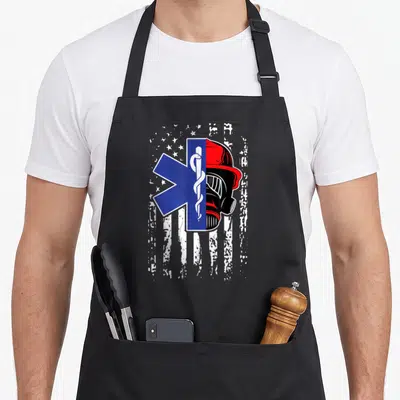 Paramedic firefighter apron - Blue Star of Life and red firefighter helmet merged on distressed white flag background — shown on a black cotton canvas apron against a white background