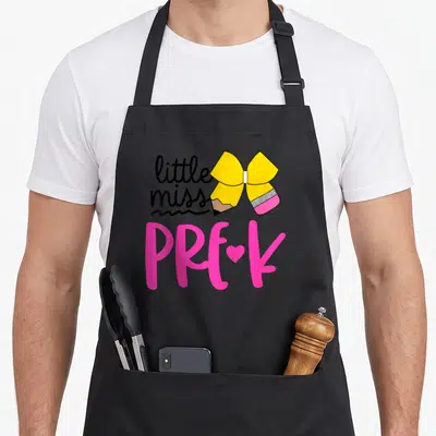 Miss bow apron - Yellow pencil bow with little miss PRE-K text and pink heart — shown on a black cotton canvas apron against a white background