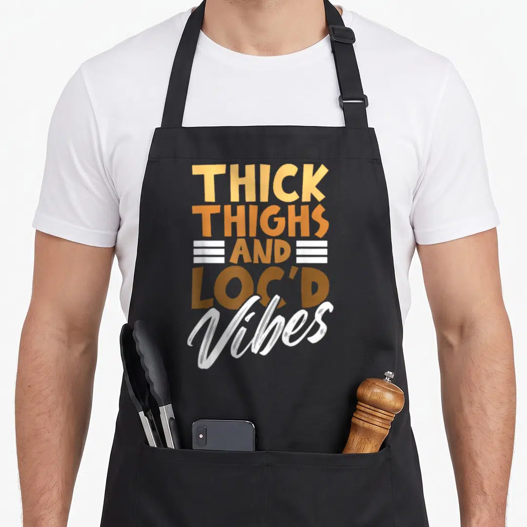 Thick african apron - Stacked typography reading THICK THIGHS AND LOC'D Vibes in yellow orange brown and white — shown on a black cotton canvas apron against a white background