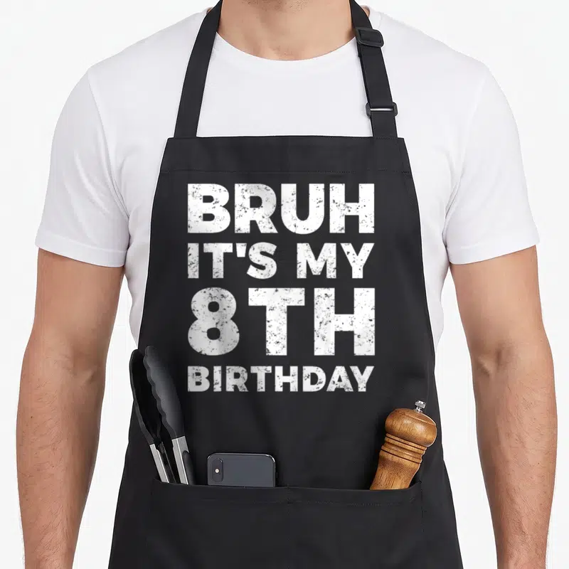 Cute bruh birthday apron - White distressed text stacked 4 lines reading BRUH IT'S MY 8TH BIRTHDAY — shown on a black cotton canvas apron against a white background