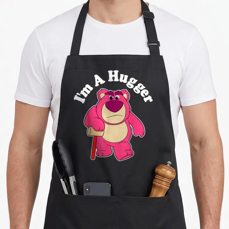 Hugger dog breed aprons - Pink bear holding red bat with arched I'm A Hugger text — shown on a black cotton canvas apron against a white background