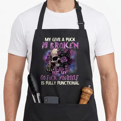 Give skull apron - Realistic skull holding up a finger surrounded by purple roses and galaxy nebula with stacked white — shown on a black cotton canvas apron against a white background