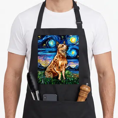 Cattle dog apron - Brown heeler dog sitting on green grass under a swirling blue starry night sky in watercolor style — shown on a black cotton canvas apron against a white background