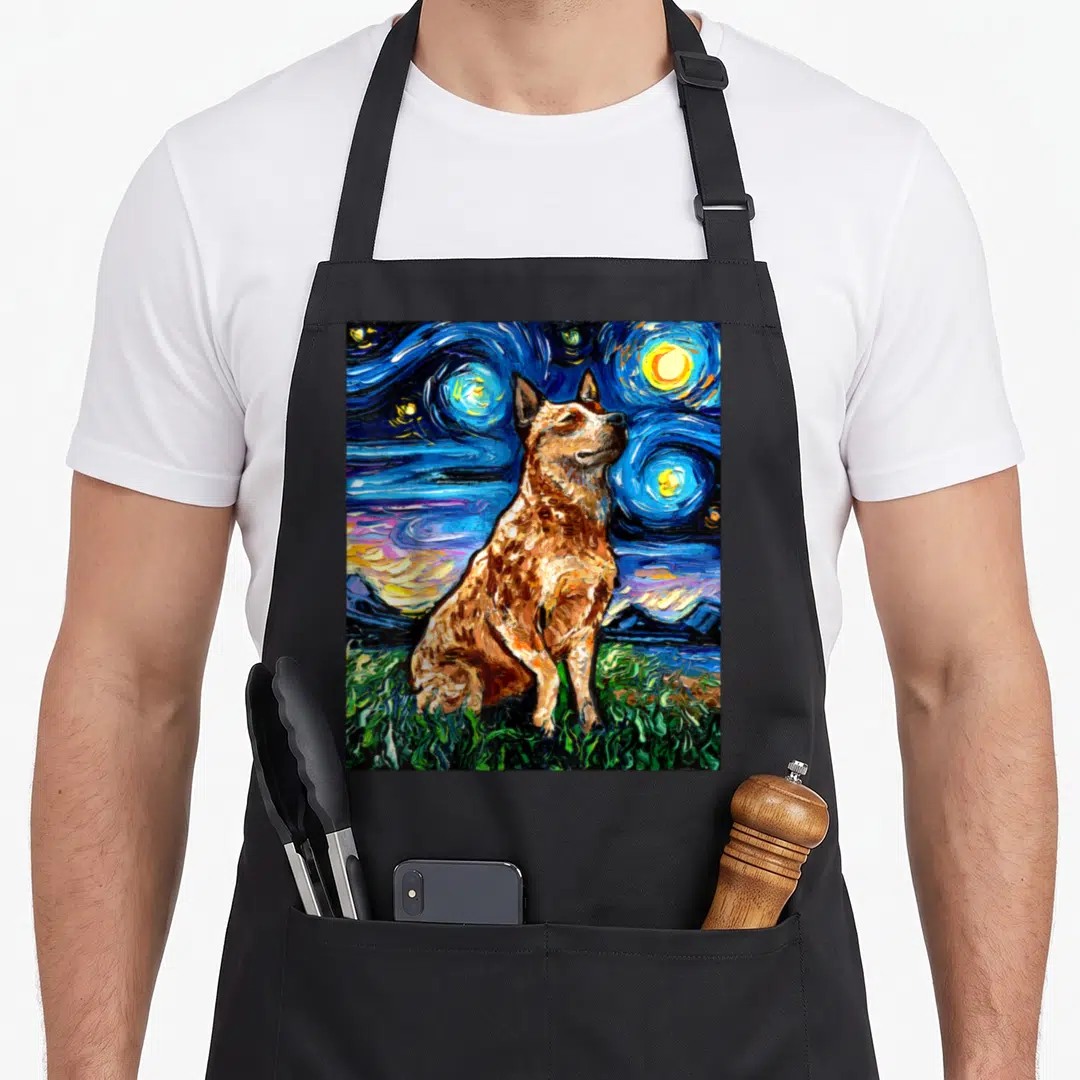 Cattle dog apron - Brown heeler dog sitting on green grass under a swirling blue starry night sky in watercolor style — shown on a black cotton canvas apron against a white background