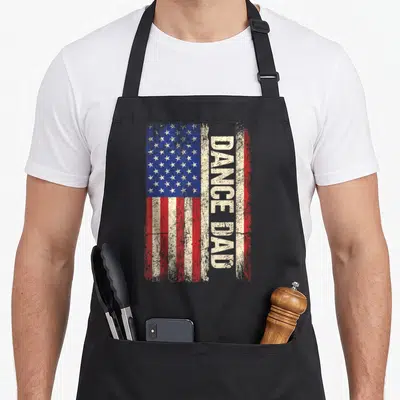 Dance american flag apron - Distressed USA flag with vertical DANCE DAD text and red white blue stripes — shown on a black cotton canvas apron against a white background