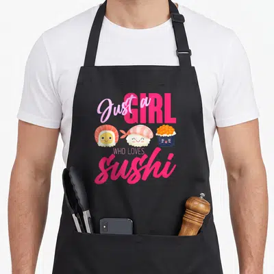 Food sushi apron - Pink and orange cartoon shrimp, fish, and roe sushi characters below 'Just a GIRL WHO LOVES Sushi' — shown on a black cotton canvas apron against a white background