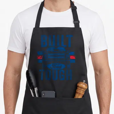 Ford truck apron - BUILT FORD TOUGH text framing a blue truck front view over red and blue stripes — shown on a black cotton canvas apron against a white background